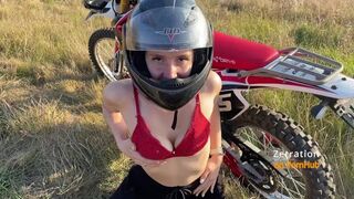 Bájos motoros fiatalasszony cumizza a motorost az enduro mezőn